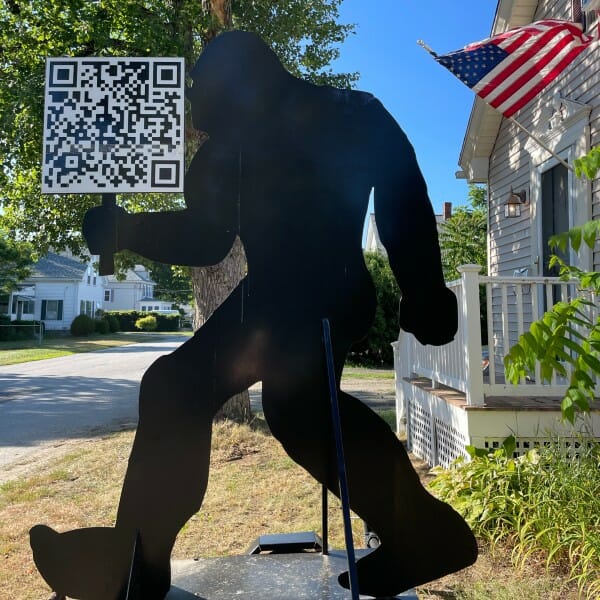 Silhouette of bigfoot holding a QR code sign